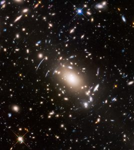 Abell S1063, a galaxy cluster, was observed by the NASA/ESA Hubble Space Telescope as part of the Frontier Fields programme. The huge mass of the cluster acts as a cosmic magnifying glass and enlarges even more distant galaxies, so they become bright enough for Hubble to see.