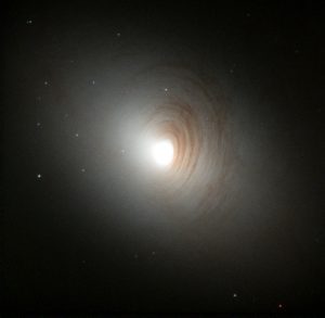 Tightly wound, almost concentric, arms of dark dust encircle the bright nucleus of the otherwise nondescript galaxy, NGC 2787, in this image created by the Hubble Heritage team. Astronomer Marcella Carollo (Swiss Federal Institute of Technology, Zurich) and collaborators used Hubble's Wide Field Planetary Camera 2 to collect the data in January 1999.