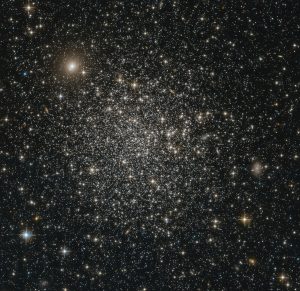 This NASA/ESA Hubble Space Telescope image reveals the simple beauty of NGC 339, a massive intermediate age star cluster in the southern constellation of Tucana (The Toucan). NGC 339 is part of the Small Magellanic Cloud (SMC), a dwarf galaxy that lies around 200 000 light-years away from us. Along with our own galaxy, the Milky Way, the SMC is one of a collection of neighbouring galaxies known as the Local Group. By measuring the brightnesses and colours of the stars of NGC 339, astronomers were able to estimate the overall age of the cluster — a method that places NGC 339 at around 6.5 billion years old. This makes it only half the age of the more common globular clusters. The relationship between massive intermediate age star clusters, such as NGC 339,  and the true globular clusters are not fully understood yet. So far none of these type of clusters has been found in the Milky Way. In this very detailed image, it is also possible to see a number of galaxies. They appear as fuzzy, extended blobs, contrasting with the sharp stars that make up NGC 339. Most obvious here are two elliptical galaxies, one towards the top left of the image and another in the centre right. These galaxies are not associated with NGC 339 but lie far in the background, across the vast expanse of the cosmos.