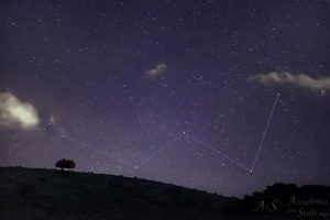 La notissima "W" di Cassiopea sorge sopra una montagna sormontata da due alberi, insieme alla stella usualmente ritenuta la più lontana visibile ad occhio nudo, evidenziata dal cerchietto sul lato destro della foto.